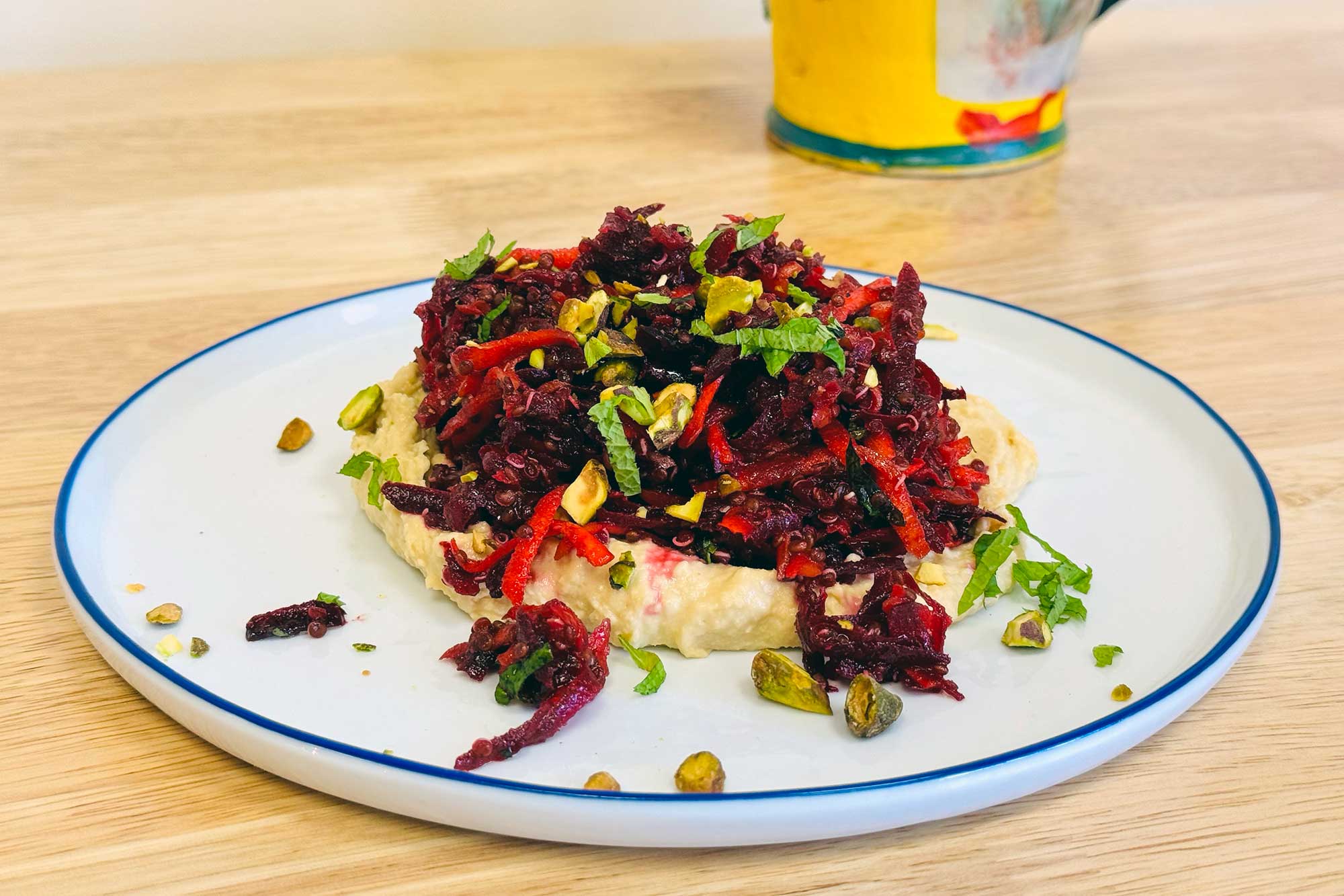 A shredded beet and carrot salad on a white plate with a blue rim