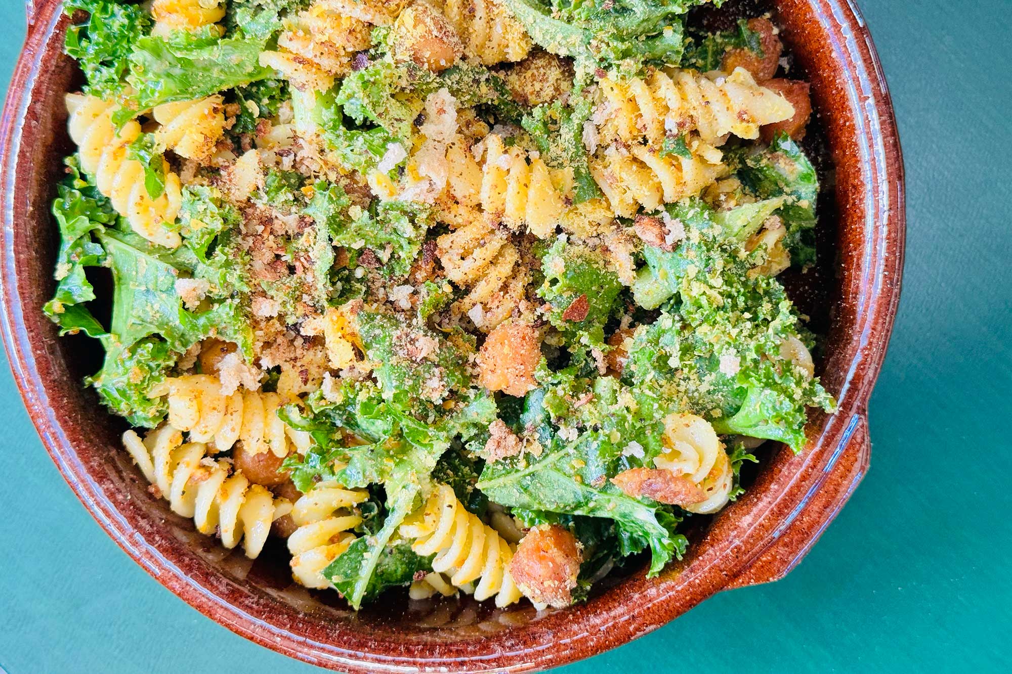 A summer pasta salad with caesar dressing, veggies, and nutritional yeast