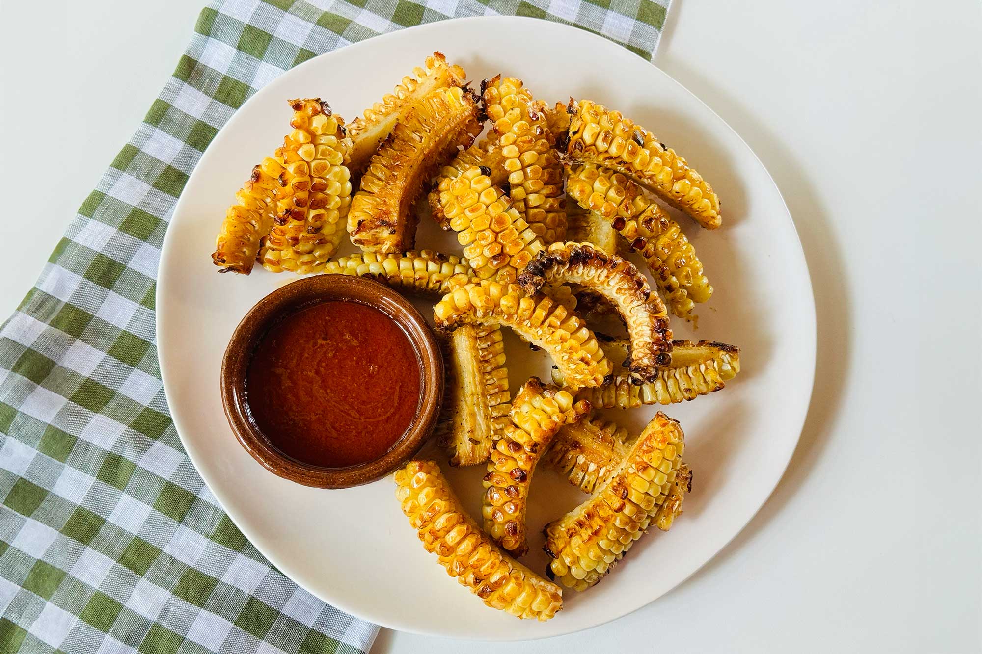 a plate of corn ribs with dipping sauce