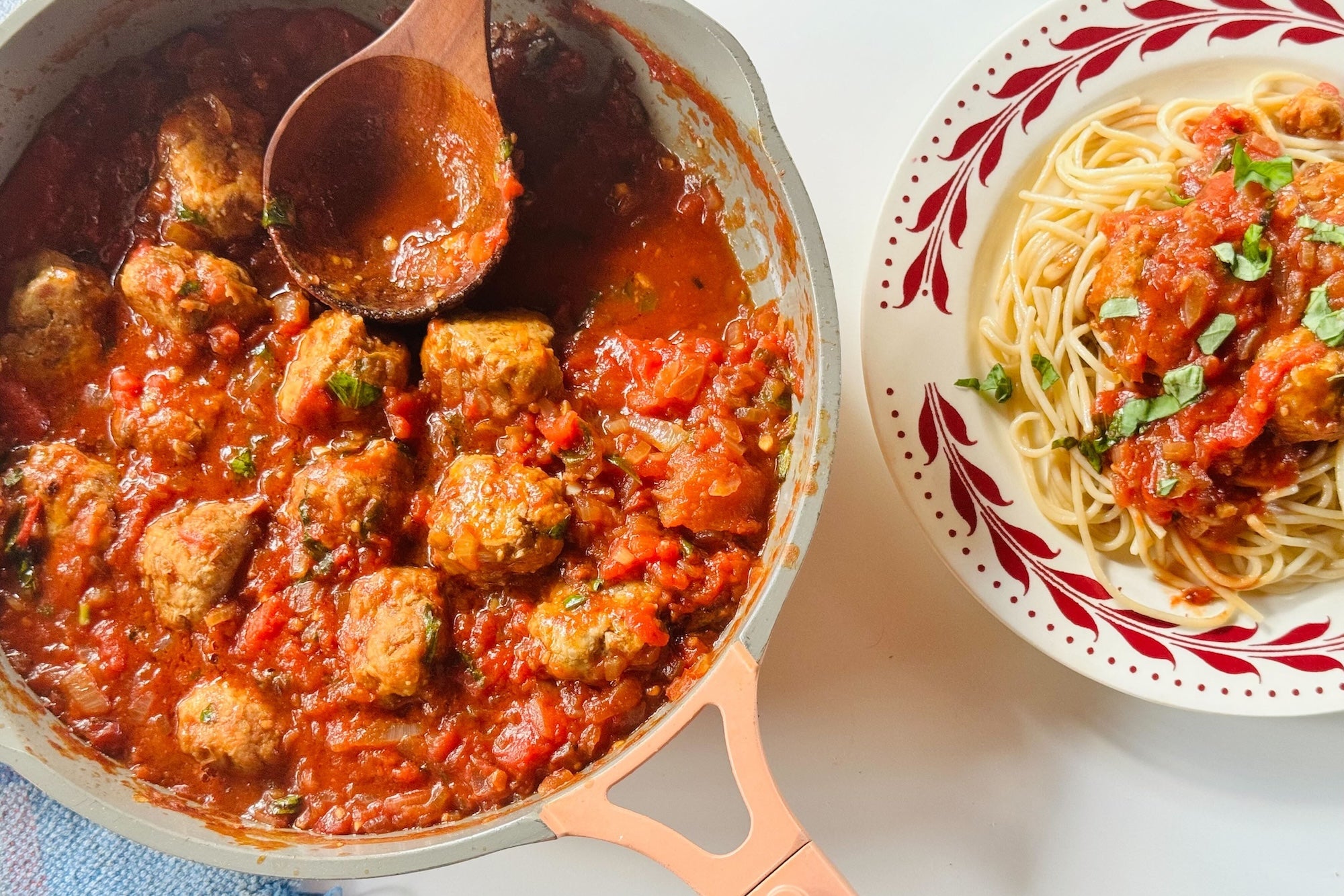 Pork and lentil meatballs in a pot beside a bowl of spagetti