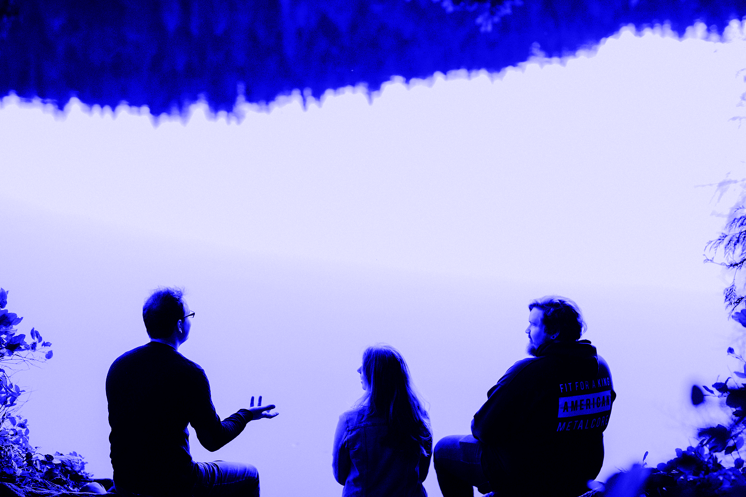 three people talking by a lake