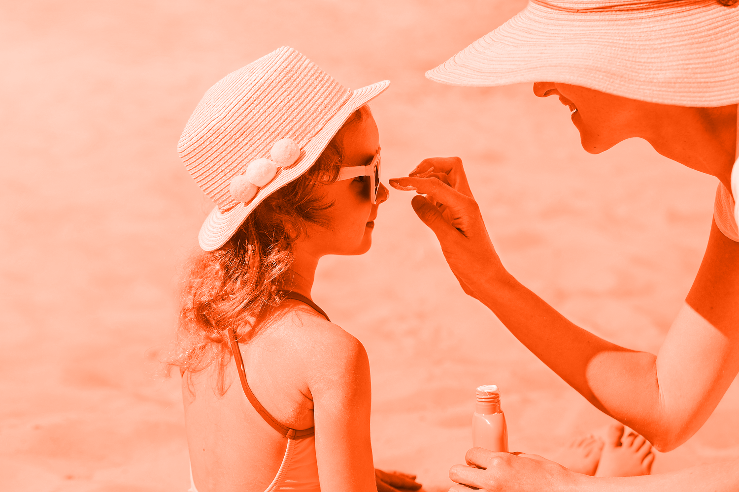woman putting sunscreen on kids face at beach