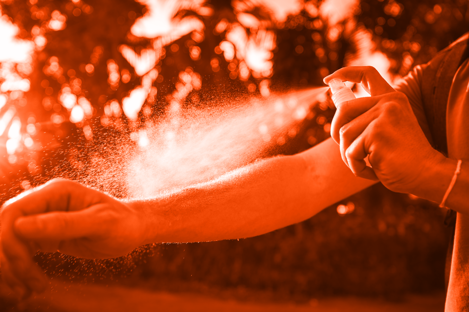 Woman applying a mist of bug spray to her arm