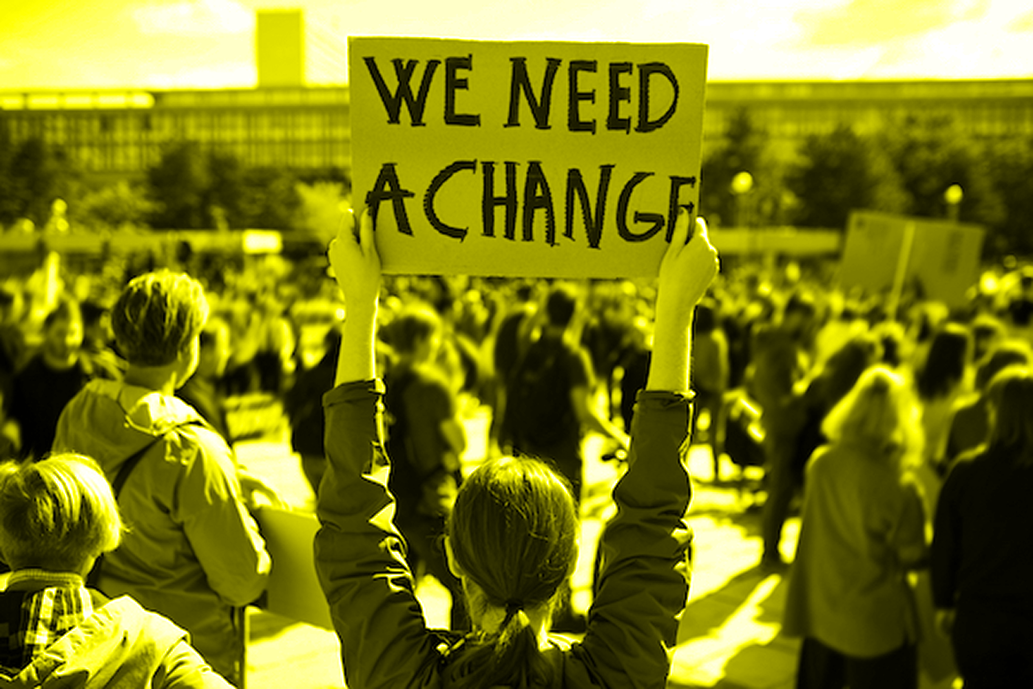 A woman from behind holding a sign over her head at a protest