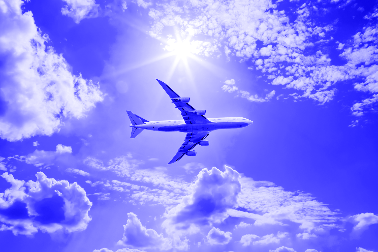 Airplane in the blue sky with clouds from below