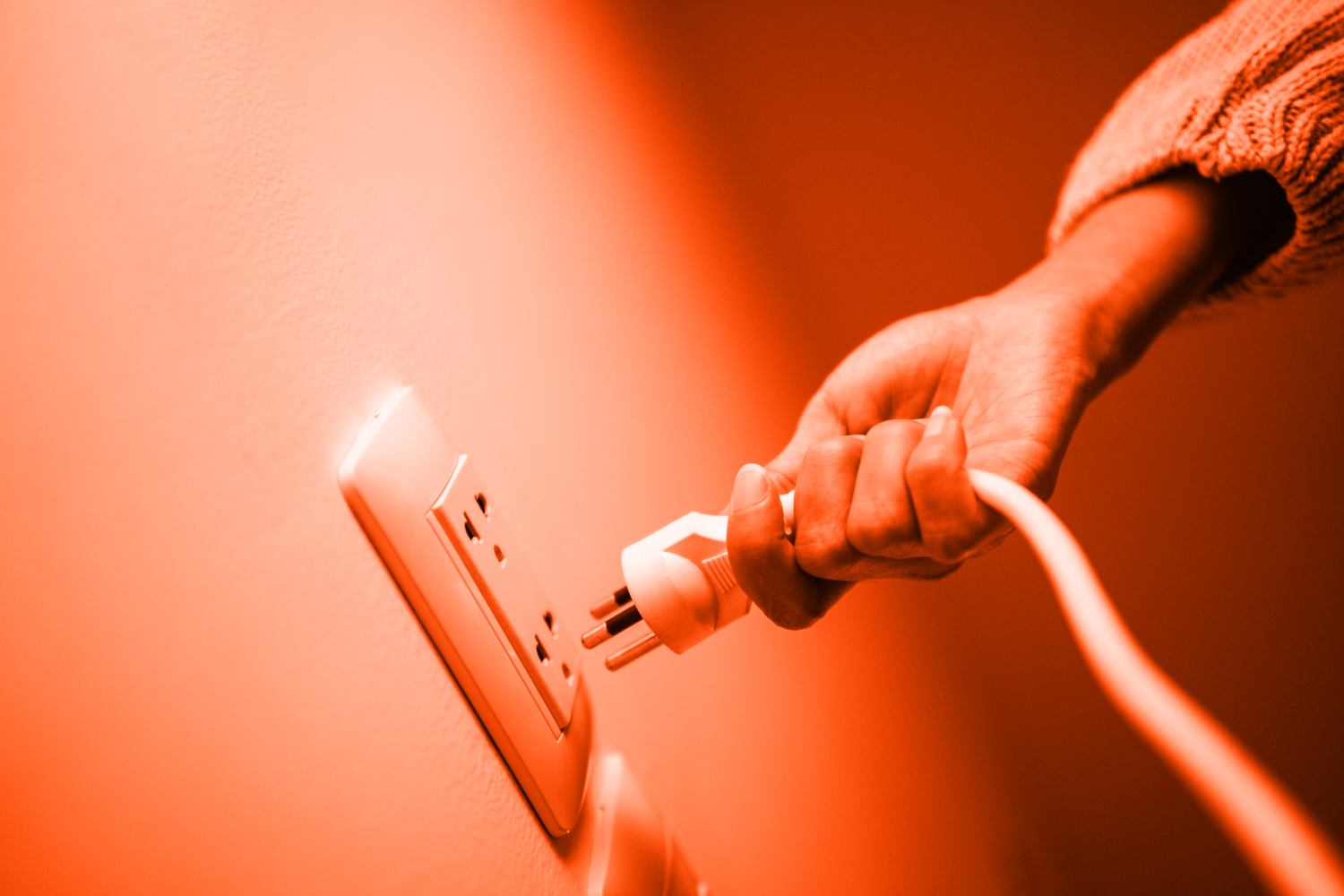 woman's hand unplugging a power cord to save energy