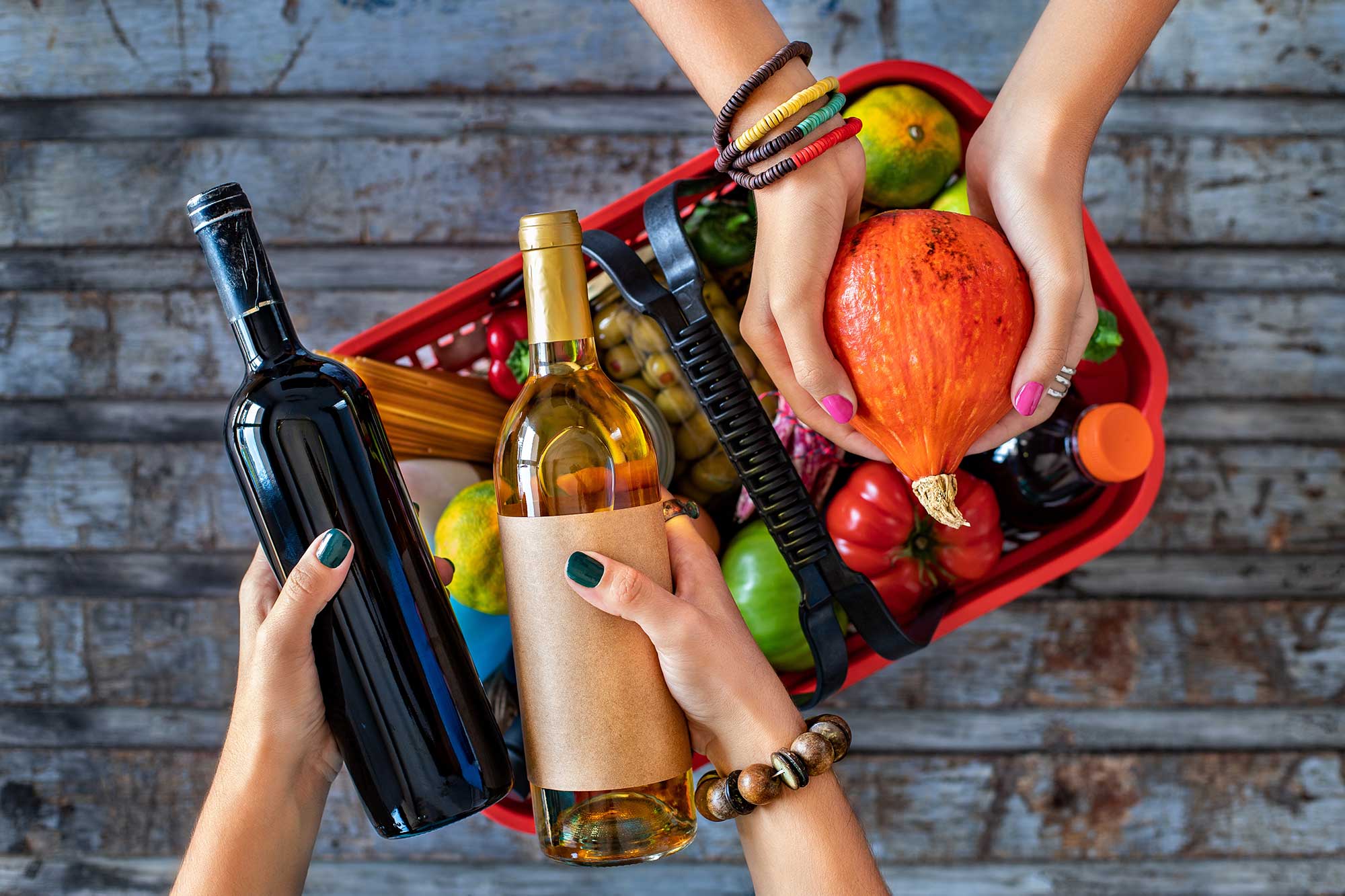 people holding wine bottles and produce