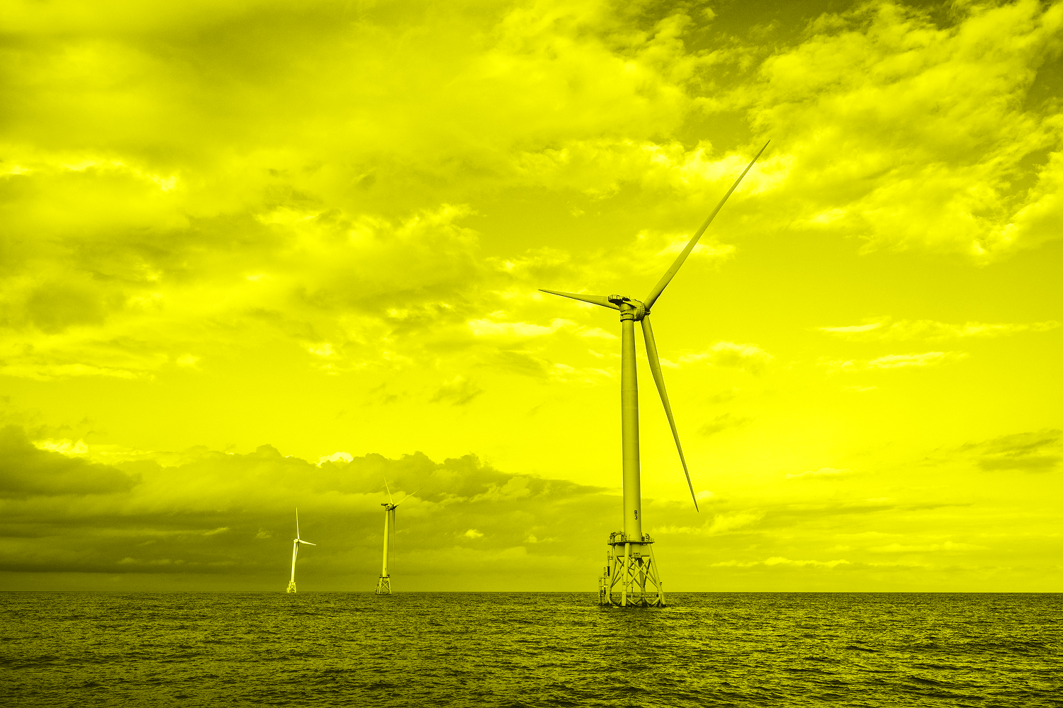 three wind turbines off shore with clouds in middle of ocean